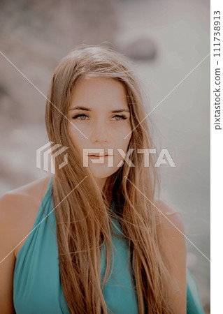 Woman sea green dress. Portrait of a happy woman with long hair in a long mint dress posing on a beach with calm sea bokeh lights on sunny day. Girl on the nature on blue sky background. Woman sea green dress. Portrait of a happy woman with long hair in a long mint dress posing on a beach with calm sea bokeh lights on sunny day. Girl on the nature on blue sky background. 111738913