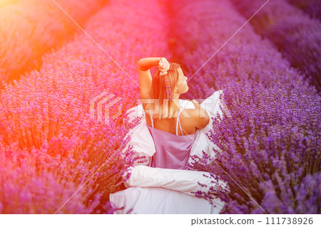 Woman lavender field. A middle-aged woman sits in a lavender field and enjoys aromatherapy. Aromatherapy concept, lavender oil, photo session in lavender Woman lavender field. A middle-aged woman sits in a lavender field and enjoys aromatherapy. Aromatherapy concept, lavender oil, photo session in lavender 111738926
