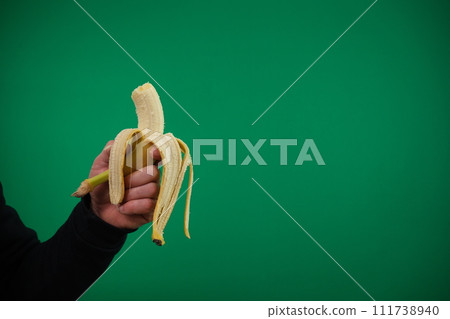 one yellow ripe banana in the man hand . advertising Green background chromakey free space 111738940