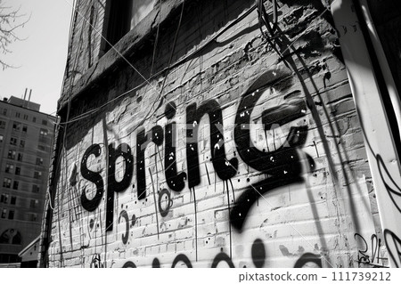 Brick wall intricately painted with the word spring in bold letters, adding a vibrant touch to the urban setting 111739212