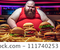 Fat man eating hamburger in fast food restaurant.  111740253