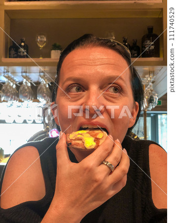 Woman Enjoying a Delicious Eclair Woman Enjoying a Delicious Eclair 111740529
