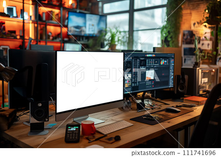 A dynamic and vibrant creative workstation with dual monitors, one displaying a blank screen, set in a cozy room filled with ambient lighting and plants. 111741696