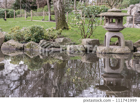 Decorative japanese stone lantern on Summer zen lake pond water. 111741999