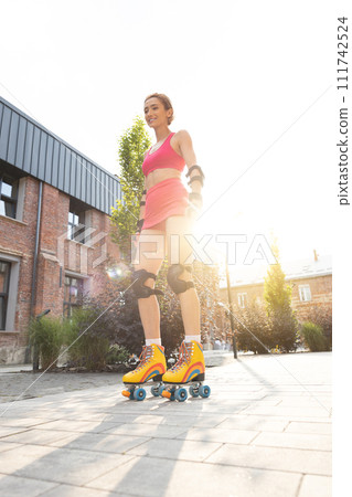 Pretty young woman standing on rollerblades 111742524