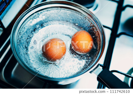 Boiled eggs are cooked in a saucepan on a gas stove for breakfast Boiled eggs are cooked in a saucepan on a gas stove for breakfast 111742610