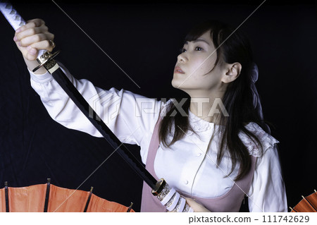 A woman pulling out a Japanese sword 111742629