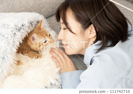 一個女人把臉靠近床上的一隻小貓 111742710