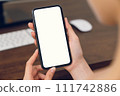 Woman hand holding smartphone mockup of blank screen for graphic display montage. 111742886