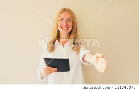 Happy smiling woman employer greets applicant holds digital tablet computer in office Happy smiling woman employer greets applicant holds digital tablet computer in office 111743075