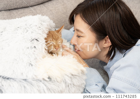Woman touching the nose of a sleeping kitten with her finger 111743285