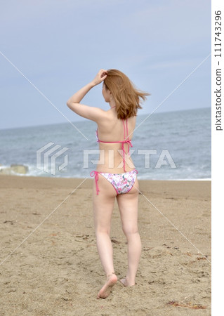 Young woman wearing a bikini swimsuit on the beach Young woman wearing a bikini swimsuit on the beach 111743296