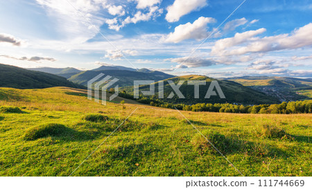rural landscape with grassy meadows. distant mountain range beneath a sky with clouds. beautiful scenery of carpathian countryside on a sunny day in early autumn 111744669
