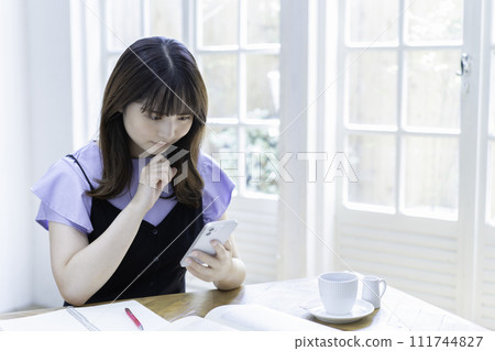 Young woman using smartphone while studying 111744827