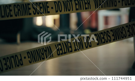 Close-up of warning yellow tape in the place of the crime scene entrance, indicating an ongoing investigation Close-up of warning yellow tape in the place of the crime scene entrance, indicating an ongoing investigation 111744951