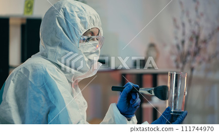 A forensic lab expert is dusting glass for fingerprints and collecting crime evidence A forensic lab expert is dusting glass for fingerprints and collecting crime evidence 111744970