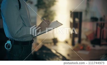 Close-up of a detective filling out reports and documenting evidence at the crime scene Close-up of a detective filling out reports and documenting evidence at the crime scene 111744973