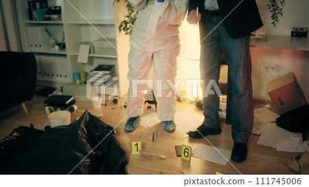 The detective and the forensic expert are discussing the crime scene while examining the evidence The detective and the forensic expert are discussing the crime scene while examining the evidence 111745006
