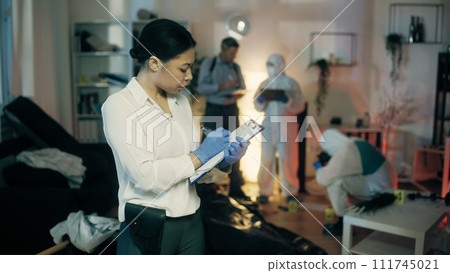 An African American police detective is documenting evidence at the crime scene in the apartment 111745021