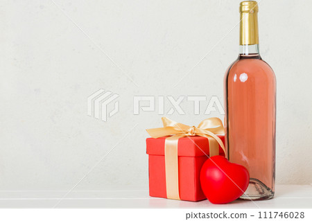 Bottle of wine on colored background for Valentine Day with gift box. Heart shaped with presrnt box perspective view with copy space Bottle of wine on colored background for Valentine Day with gift box. Heart shaped with presrnt box perspective view with copy space 111746028