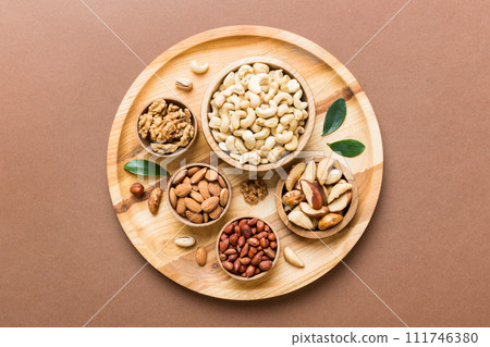 mixed nuts in wooden bowl. Mix of various nuts on colored background. pistachios, cashews, walnuts, hazelnuts, peanuts and brazil nuts mixed nuts in wooden bowl. Mix of various nuts on colored background. pistachios, cashews, walnuts, hazelnuts, peanuts and brazil nuts 111746380