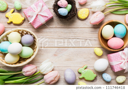 Easter frame with eggs, gift box and tulip on a colored background. The minimal concept. Top view Happy Easter composition. Card with a copy space of the place for the text Easter frame with eggs, gift box and tulip on a colored background. The minimal concept. Top view Happy Easter composition. Card with a copy space of the place for the text 111746418