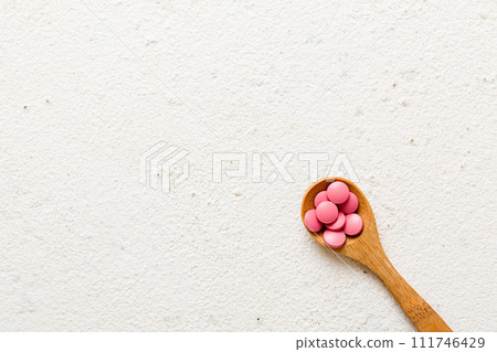 Vitamin capsules in a spoon on a colored background. Pills served as a healthy meal. Red soft gel vitamin supplement capsules on spoon Vitamin capsules in a spoon on a colored background. Pills served as a healthy meal. Red soft gel vitamin supplement capsules on spoon 111746429