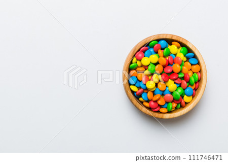 Multicolored candies in a bowl on a colored background. birthday and holiday concept. Top view with copy space 111746471