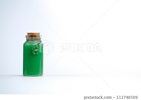 Phial with green liquid and four leaf clover shamrock on white background 111746509