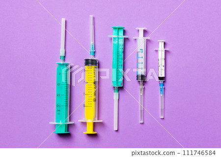 Top view of medical syringes with needles at purple background with copy space. Injection treatment concept Top view of medical syringes with needles at purple background with copy space. Injection treatment concept 111746584