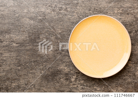 Top view of empty orange plate on cement background. Empty space for your design Top view of empty orange plate on cement background. Empty space for your design 111746667