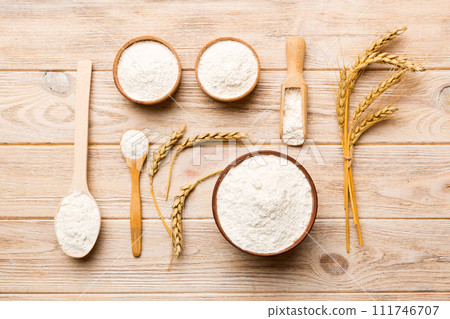 Flat lay of Wheat flour in wooden bowl with wheat spikelets on colored background. world wheat crisis 111746707