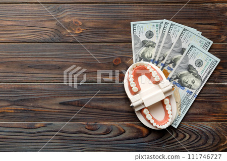 Closeup model of a human jaw with white teeth and dollar bill. Dentistry conceptual photo. Prosthetic dentistry. False teet top view with copy space Closeup model of a human jaw with white teeth and dollar bill. Dentistry conceptual photo. Prosthetic dentistry. False teet top view with copy space 111746727