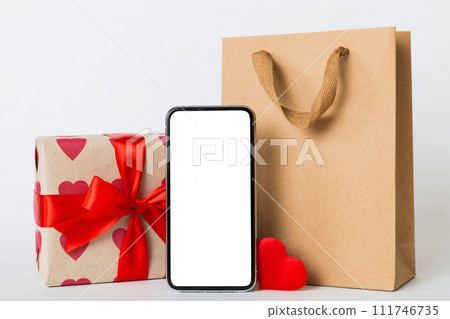 mobile phone with blank screen on colored background with hearts, calendar and gift box, valentine day concept perspertive view flat lay 111746735