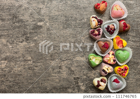 chocolate sweets in the form of a heart with fruits and nuts on a colored background. top view with space for text, holiday concept chocolate sweets in the form of a heart with fruits and nuts on a colored background. top view with space for text, holiday concept 111746765