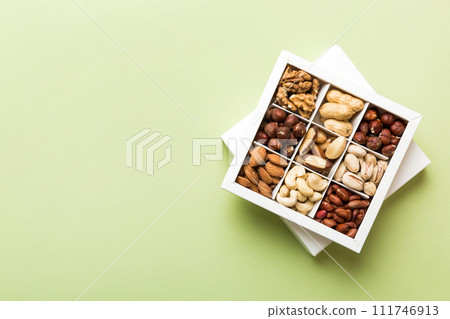 Various varieties of nuts lying in paper box on table background. Top view. Healthy food. Close up, copy space, top view, flat lay. Walnut, pistachios, almonds, hazelnuts and cashews Various varieties of nuts lying in paper box on table background. Top view. Healthy food. Close up, copy space, top view, flat lay. Walnut, pistachios, almonds, hazelnuts and cashews 111746913