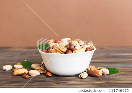 mixed nuts in bowl. Mix of various nuts on colored background. pistachios, cashews, walnuts, hazelnuts, peanuts and brazil nuts 111746915
