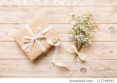 Gift or present box and flower gypsophila on light table top view. Greeting card. Flat lay style with copy space Gift or present box and flower gypsophila on light table top view. Greeting card. Flat lay style with copy space 111746943