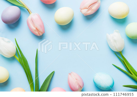 Happy Easter composition. Easter eggs on colored table with yellow Tulips. Natural dyed colorful eggs background top view with copy space Happy Easter composition. Easter eggs on colored table with yellow Tulips. Natural dyed colorful eggs background top view with copy space 111746955