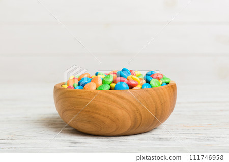 Multicolored candies in a bowl on a colored background. birthday and holiday concept. Top view with copy space 111746958