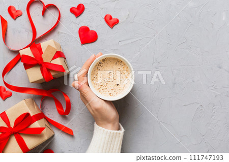 Flat lay of heart shaped cup of black coffee in the hands of women on colored background with copy space top view. Valentine day and holiday concept 111747193