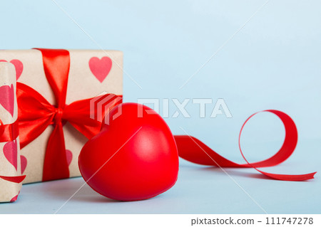 gift box with red bow and red heart on colored background. Perspective view. Flat lay gift box with red bow and red heart on colored background. Perspective view. Flat lay 111747278