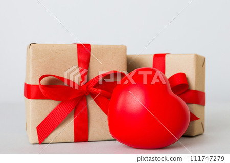 gift box with red bow and red heart on colored background. Perspective view. Flat lay gift box with red bow and red heart on colored background. Perspective view. Flat lay 111747279