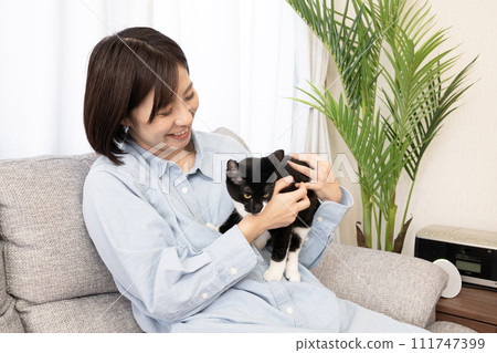 一個女人坐在沙發上抱著一隻小貓 111747399