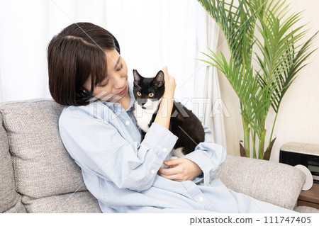 A woman sitting on a sofa and holding a kitten A woman sitting on a sofa and holding a kitten 111747405