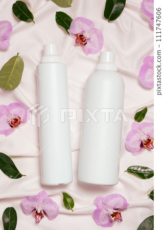 Liquid laundry detergent and fabric softener on bedding, orchid flowers, top view Liquid laundry detergent and fabric softener on bedding, orchid flowers, top view 111747606