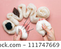 woman hand holding skein of wool and needle felting kit. felted woolen wool on pink background, handicraft from above. flat lay 111747669