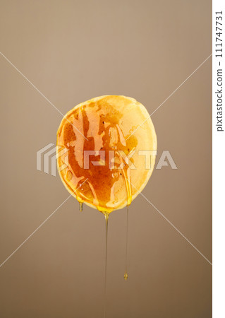 One pancake in honey on a brown background One pancake in honey on a brown background 111747731