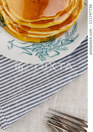 A stack of pancakes with honey on a vintage plate on the table. Breakfast. A stack of pancakes with honey on a vintage plate on the table. Breakfast. 111747736