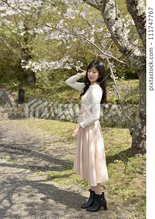 A young slim woman posing in a cherry blossom park A young slim woman posing in a cherry blossom park 111747767